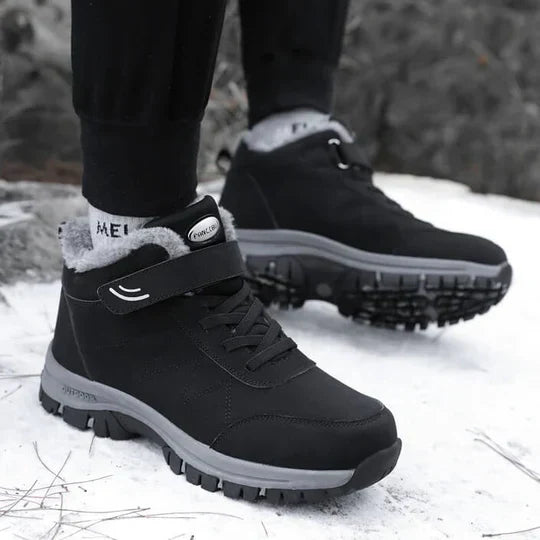 Person wearing black fleece-lined boots with a strap and laces, standing on snow 4