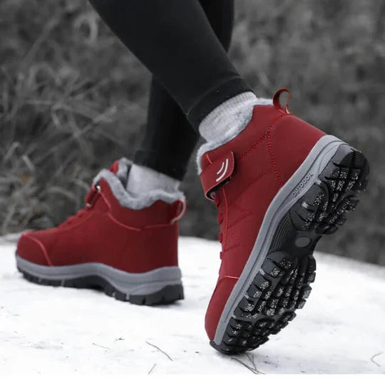 Person walking on snow in red fleece-lined boots, the sole tread visible on the raised foot 6