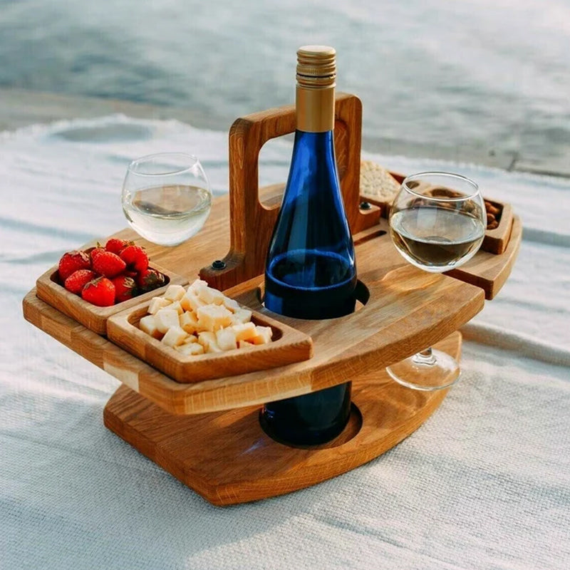 Wooden wine table on a white blanket holding a blue bottle, two glasses, strawberries and cheese cubes 1