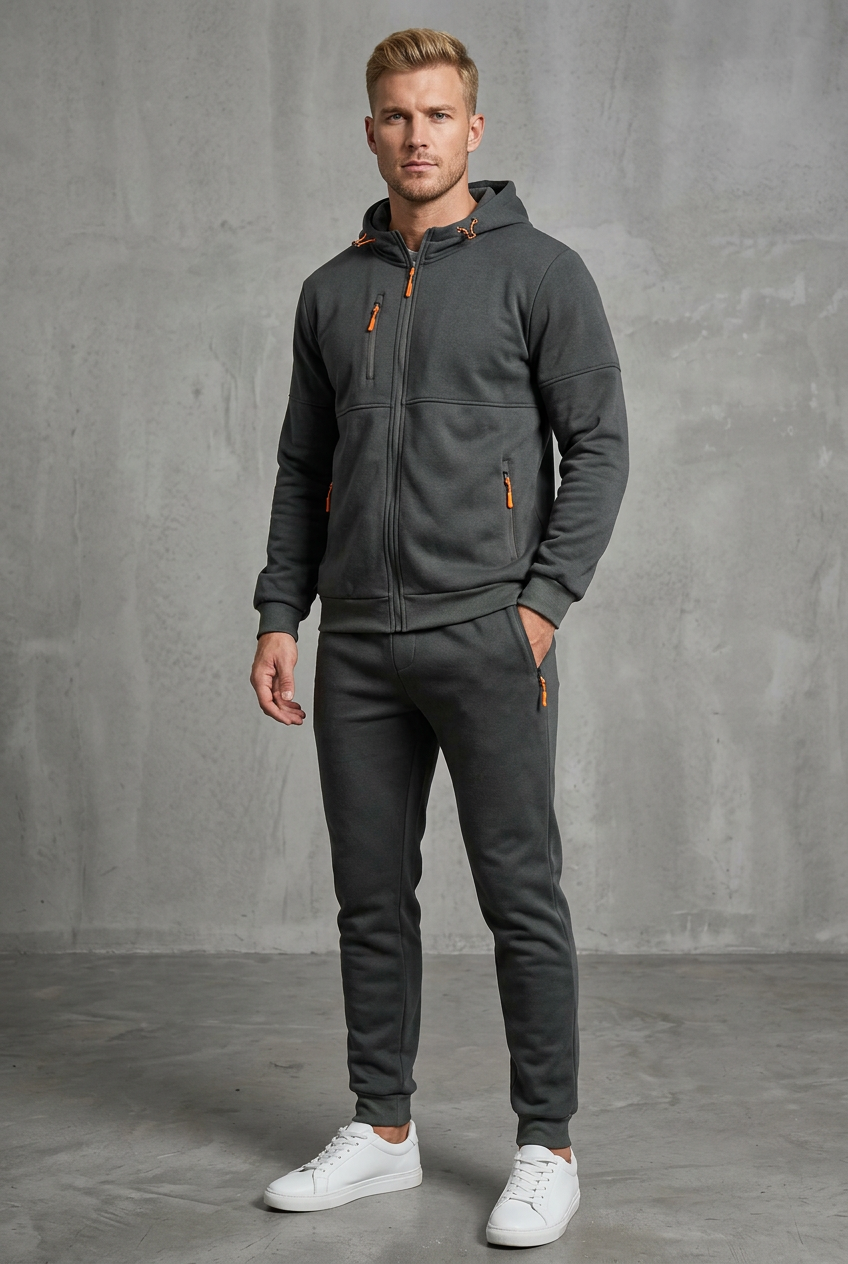 Man in dark charcoal gray hooded zip jacket and joggers with orange zipper pulls, hand in pocket 4