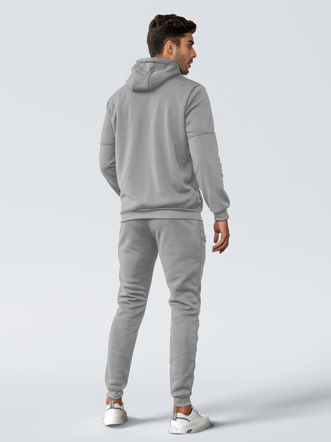 Back view of a man wearing a light gray hoodie and matching joggers, looking over his shoulder 11