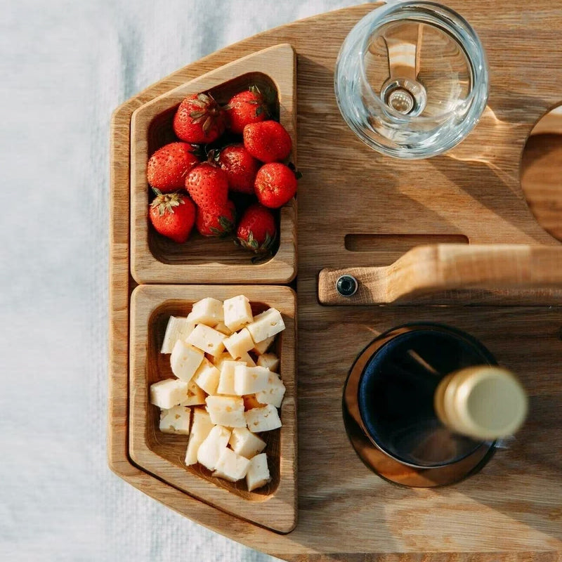 Close-up from above of two wooden snack trays holding strawberries and cheese cubes beside a glass and bottle 9