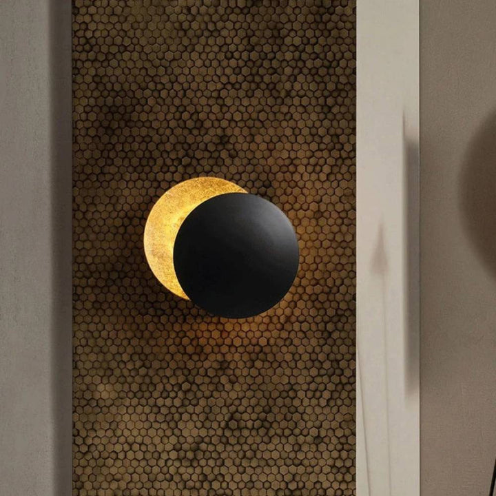 Black front disc overlapping a glowing gold-leaf disc, mounted on a honeycomb-patterned wall panel 2