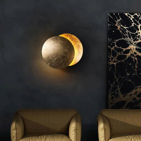 Gold overlapping discs glowing on a dark wall beside marble-pattern art, above two armchairs 3