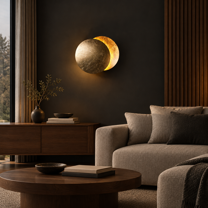 Gold-leaf disc lamp glowing on a dark wall above a wooden sideboard and beige sofa 1