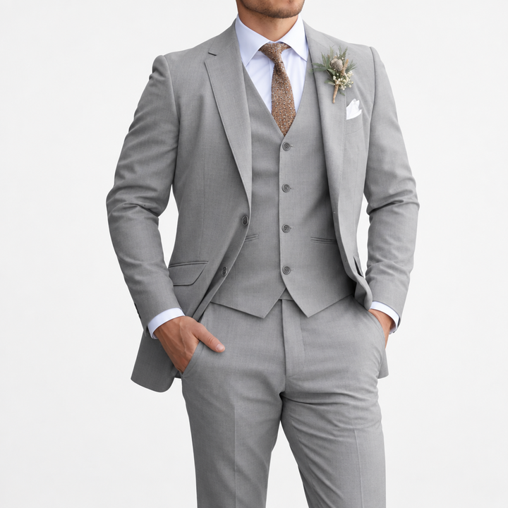 Model in the gray three-piece suit with white shirt, brown tie and dried-flower boutonniere on white background 8