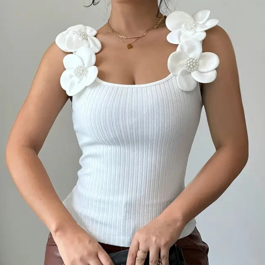 Frau in weißem, geripptem Tanktop mit Blumenapplikationen und Perlendetails.