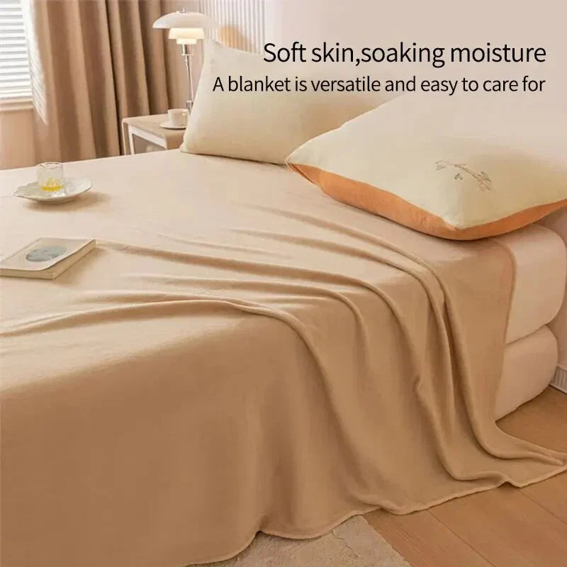 Beiges Bett mit weicher Decke, Kissen und Nachttischlampe im Schlafzimmer, gemütliche Einrichtung.