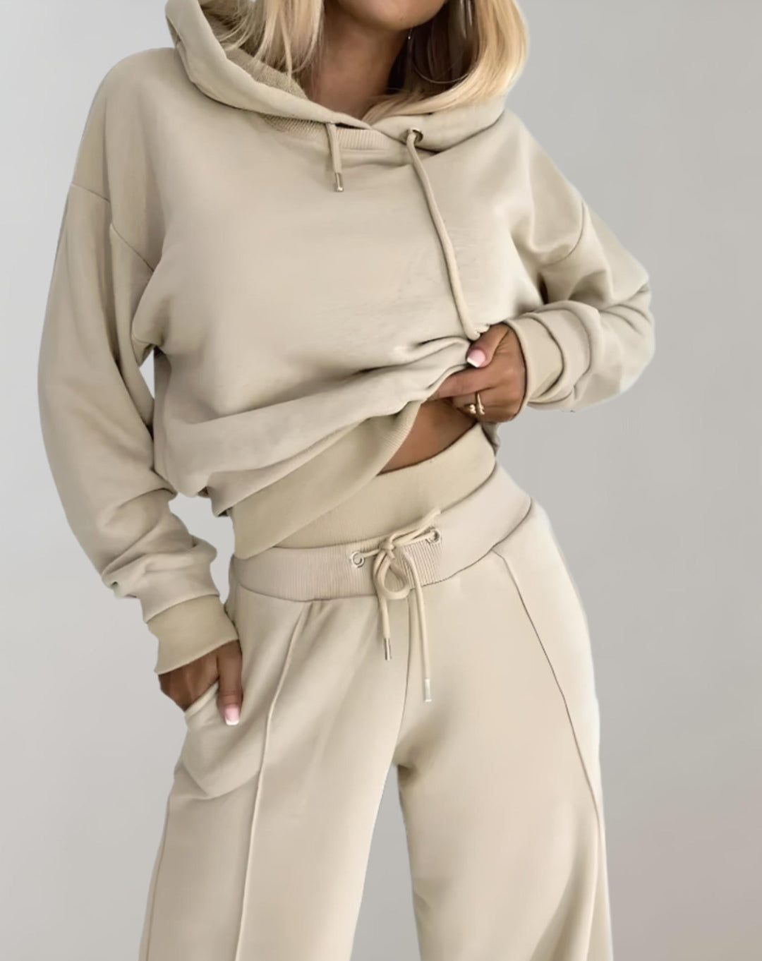 Frau in beigem Hoodie und Jogginghose, Freizeitmode, bequeme Damenbekleidung, Streetwear.