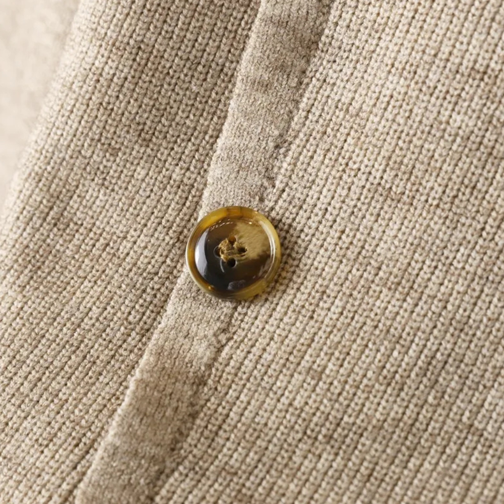 Beiger Strickstoff mit braunem Knopf, Nahaufnahme, Textur, Mode, Detailansicht.