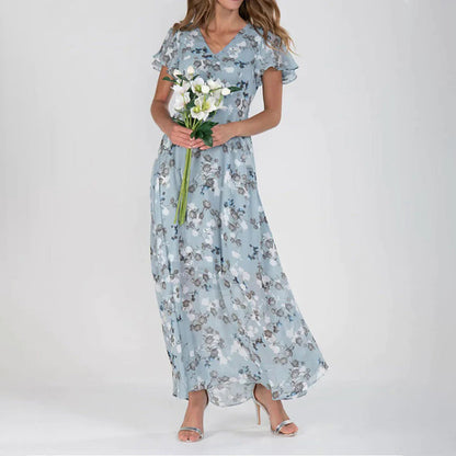 Frau in blauer, geblümter Maxikleid, hält weiße Blumen, elegante Mode, Sommerkleid.