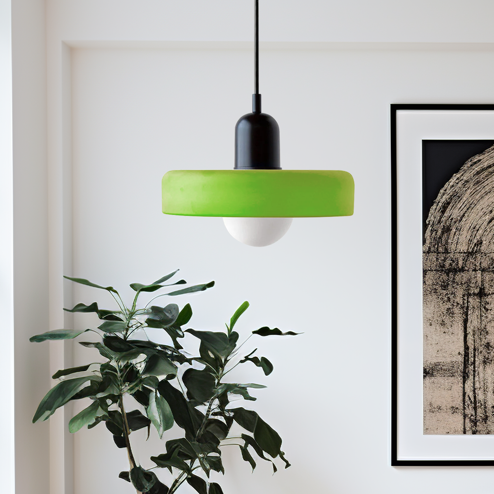 Lime green glass pendant with black cap hanging beside a leafy plant and a framed print 52