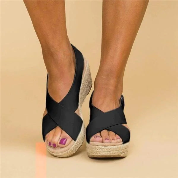 Front view of black crisscross wedge sandals worn on feet, showing the open toe and braided platform 9