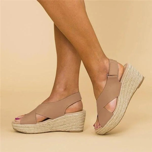 Tan crisscross wedge sandals with jute soles, worn on a beige background, shown from the side 2