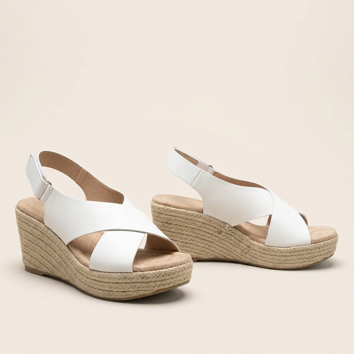 Pair of white crisscross wedge sandals with padded footbeds and braided wedges on a cream background 15