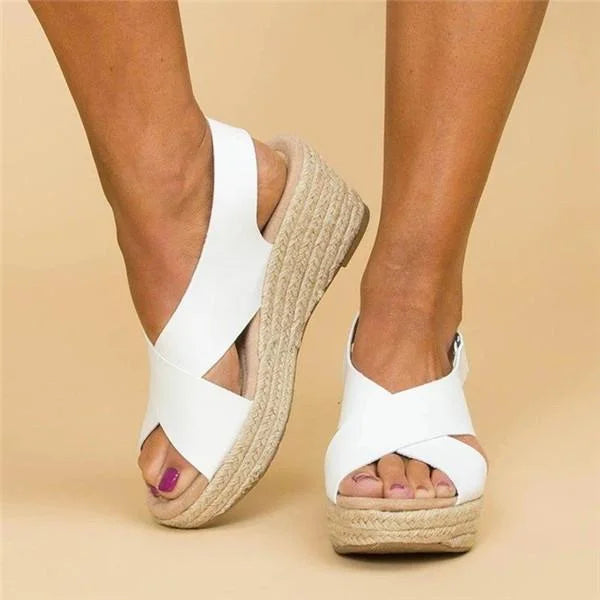 White crisscross-strap wedge sandals worn on feet, showing the open toe, heel strap and braided jute wedge 11