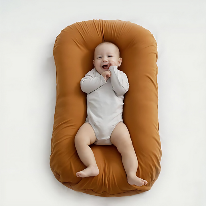 Overhead view of a smiling baby in a white bodysuit on a rust orange cushion 3