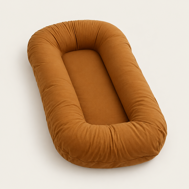 Empty caramel brown oval pillow with raised rim and flat center, shown from an angle 9