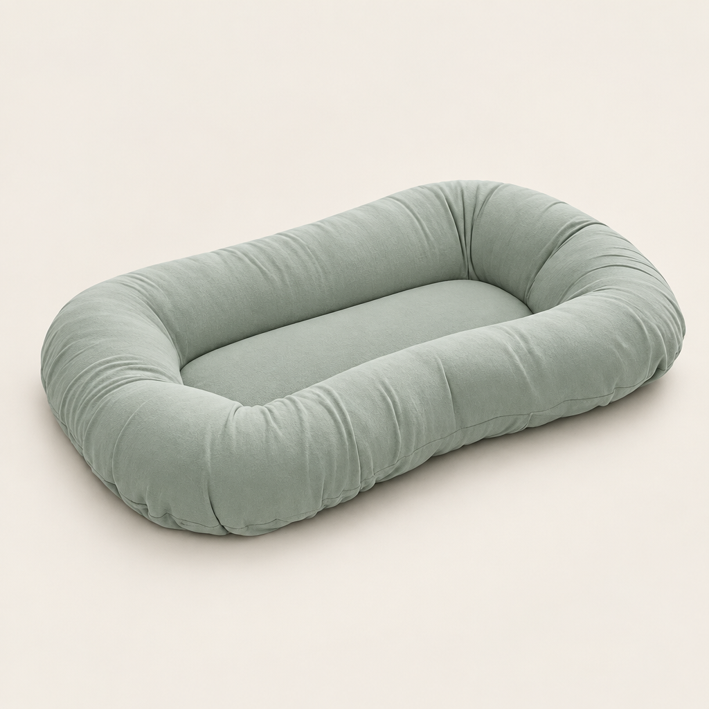 Empty sage green oval pillow with raised rim and flat center, shown from an angle 8