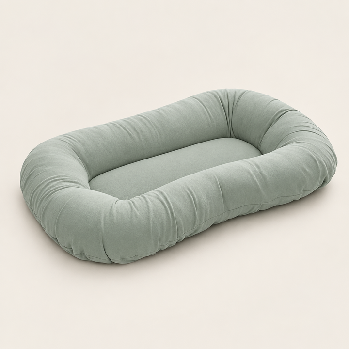 Empty sage green oval pillow with raised rim and flat center, shown from an angle 8
