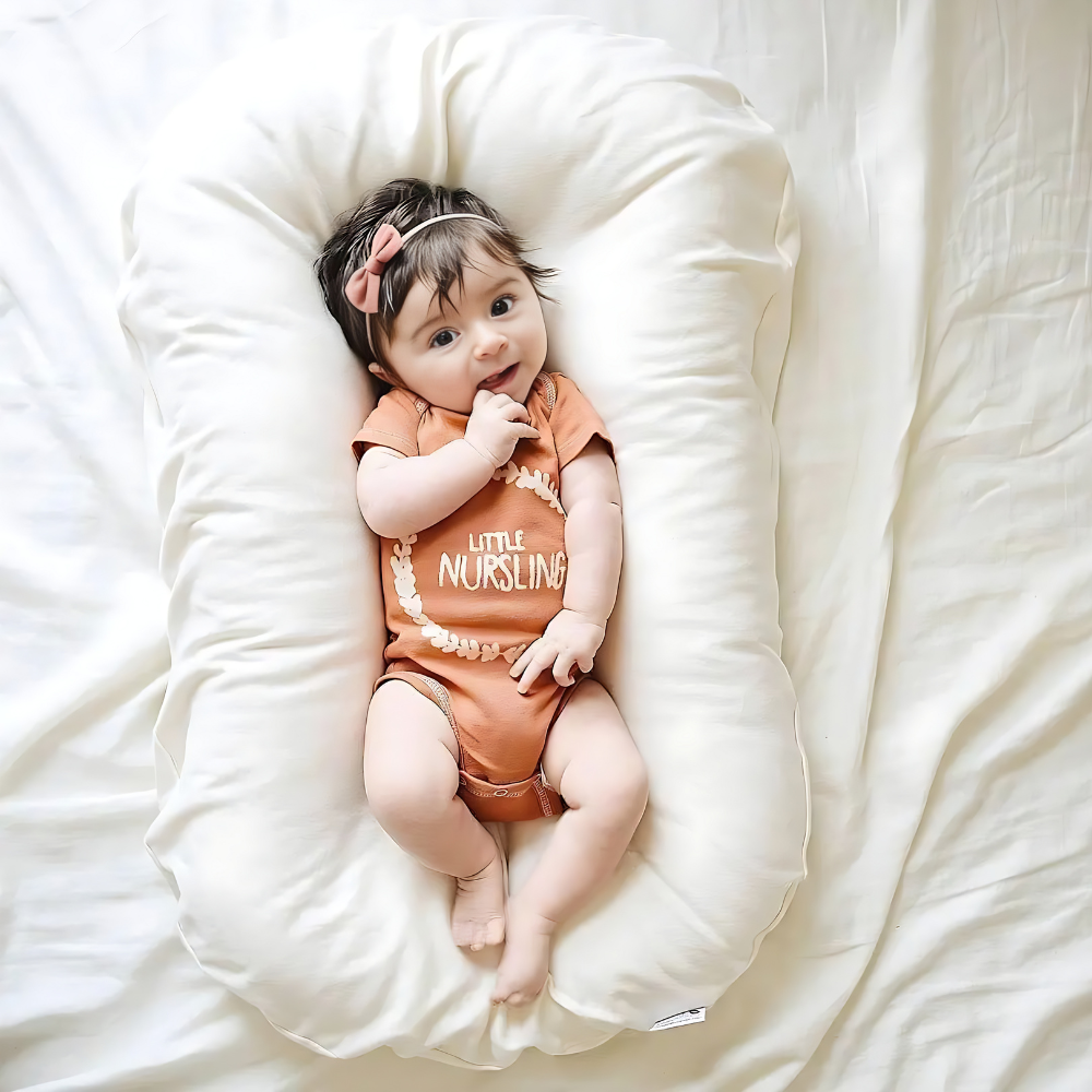 Overhead view of a baby with a pink hair bow resting on a cream white lounger 4