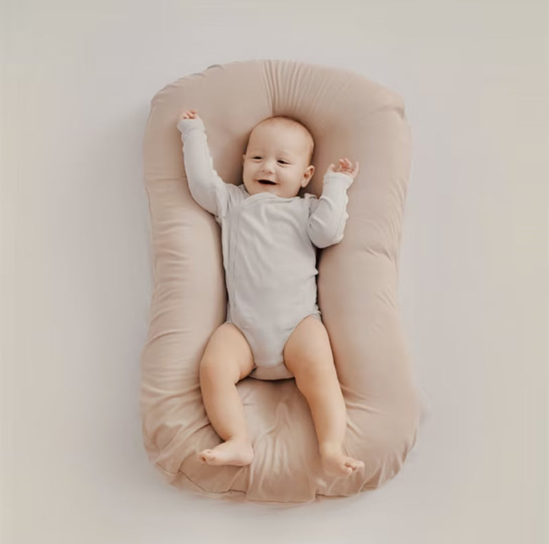 Top view of a cheerful baby with raised arms on a soft beige lounger 6