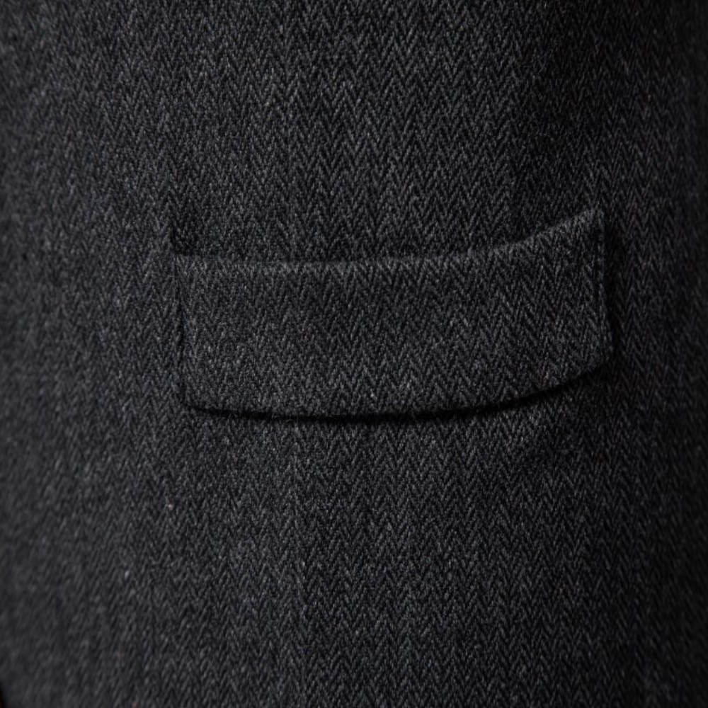 Dunkelgrauer Wollstoff mit Fischgrätmuster, Detailansicht einer Anzugtasche.