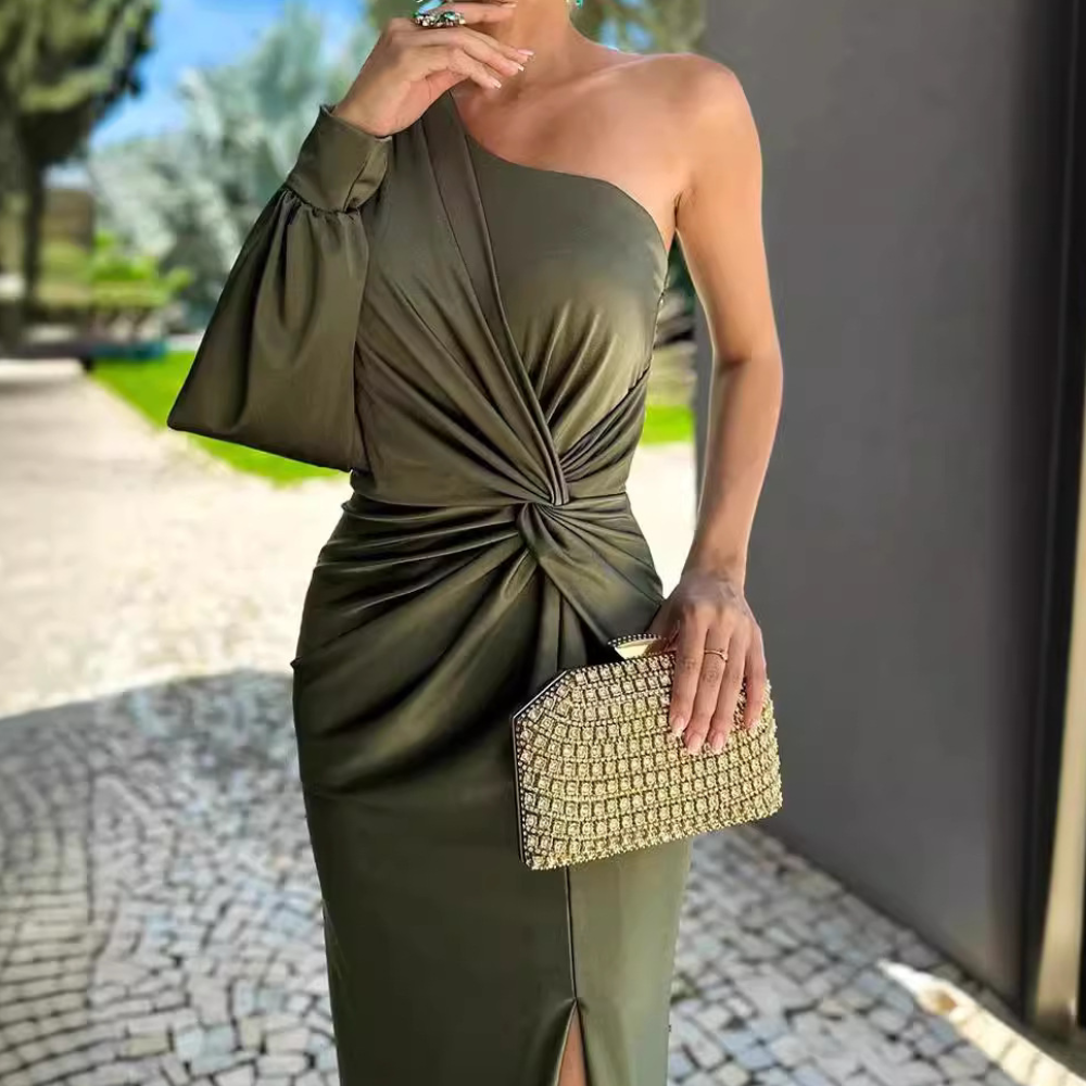 Frau in olivgrünem, schulterfreiem Kleid mit Knoten, hält goldene Clutch, elegantes Outfit.