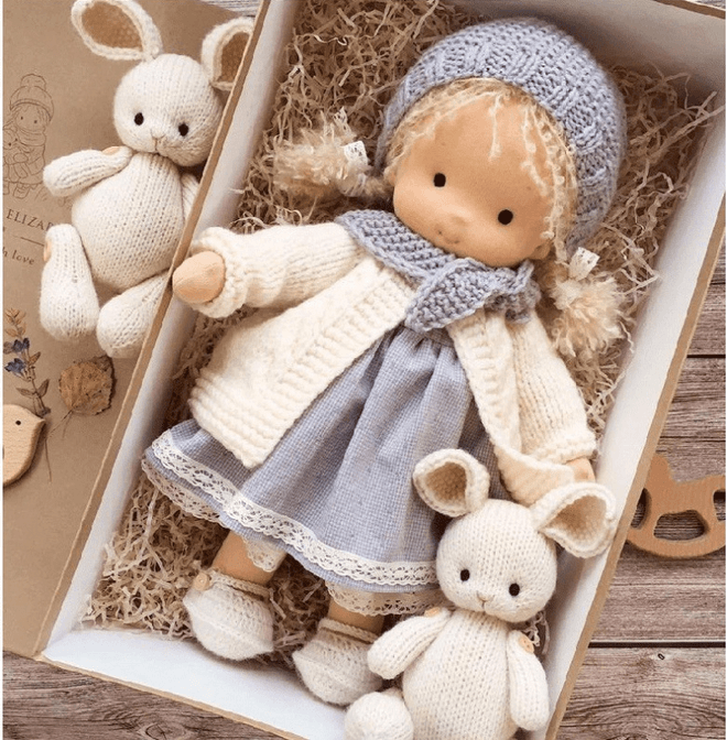 Doll with gray knit bonnet, cream cardigan and lace-trimmed gray dress in gift box with two knitted bunnies 4