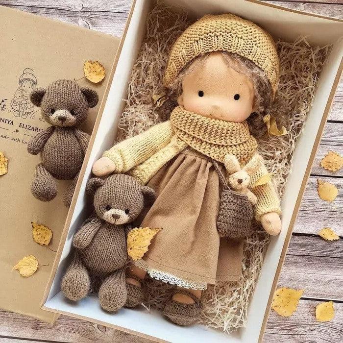 Doll in mustard knit hat, cowl and brown dress, boxed with two knitted brown bears among autumn leaves 6