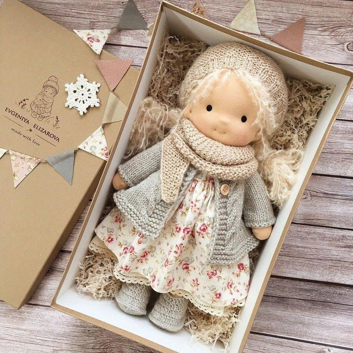 Doll with pale curly hair in a beige hat, gray cardigan and floral dress in an open gift box 7