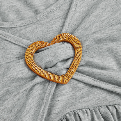 Herzförmige, goldene Brosche auf grauem Stoff, Schmuckaccessoire, elegant, modisch.