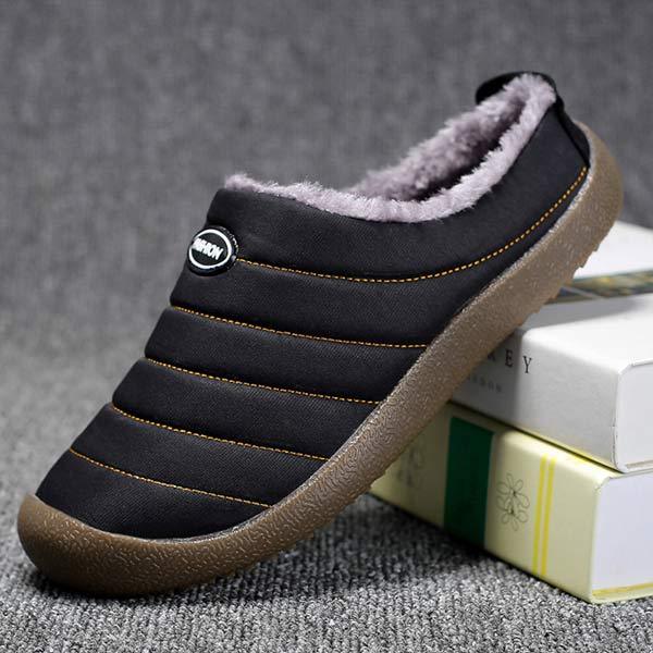 Single black slipper tilted on books, showing orange stitching and textured brown sole 10