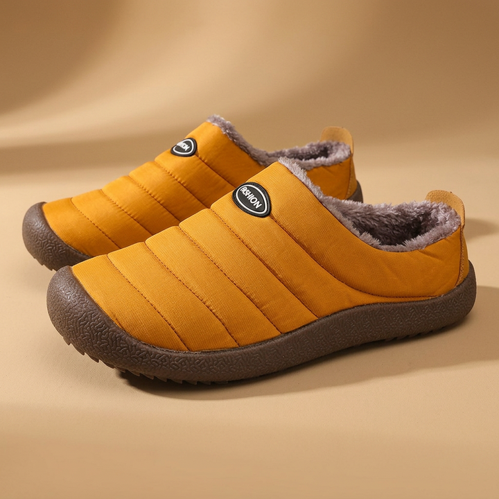 Pair of mustard yellow quilted slippers with fleece lining on a tan studio background 20