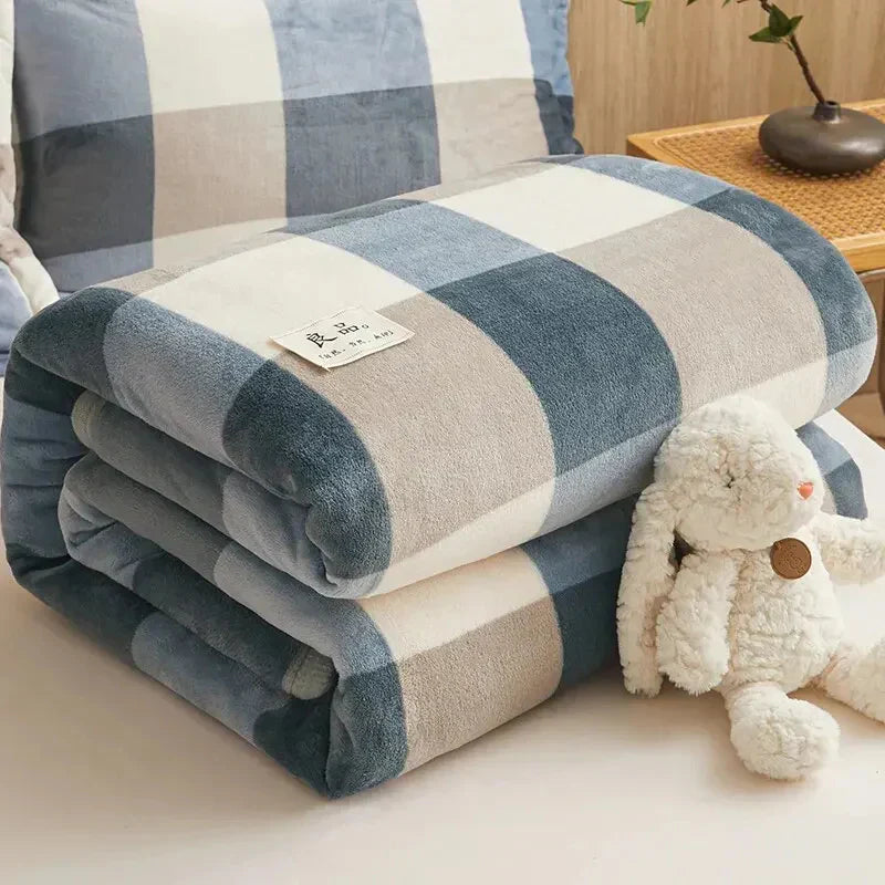 Blau-weiß kariertes Fleece-Plaid auf Bett, weiches Kuscheltier daneben, gemütliche Schlafzimmerdeko.