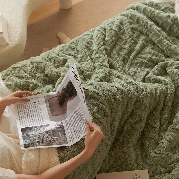 Person liest Zeitschrift auf grüner, gestrickter Decke im Wohnzimmer, gemütliche Wohnkultur.