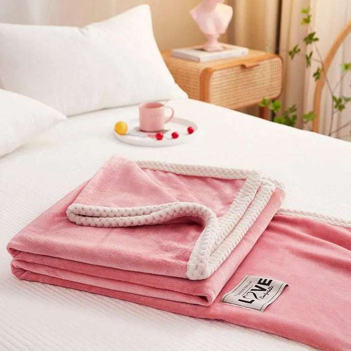 Rosa Kuscheldecke aus Fleece mit weißem Rand auf Bett, gemütliche Schlafzimmerdekoration.