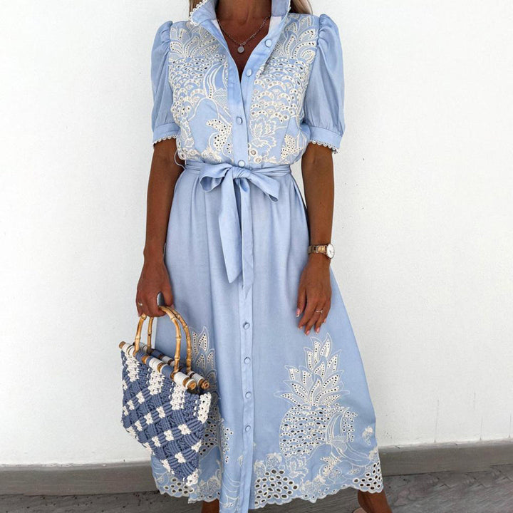 Frau in hellblauer Maxikleid mit Spitze, hält geflochtene Tasche, elegantes Sommeroutfit.