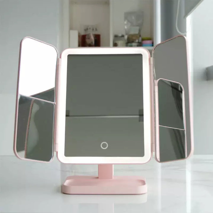 Pink tri-fold mirror fully opened on a marble surface, with the center panel's LED ring lit and touch button visible 3
