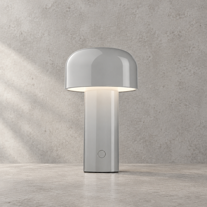 Glossy light gray lamp lit against a textured wall, touch button on the stem 32