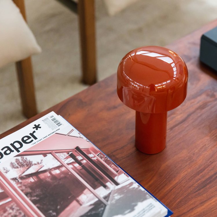 Red-orange mushroom lamp seen from above on a wooden coffee table next to a magazine 13