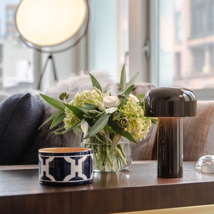 Black glossy mushroom lamp on a wooden table beside a flower bouquet and a patterned bowl 15