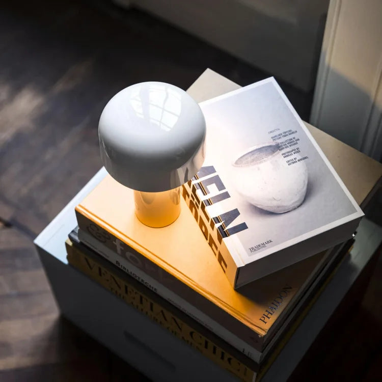 White mushroom lamp glowing warmly on a pile of coffee-table books, photographed from above 20