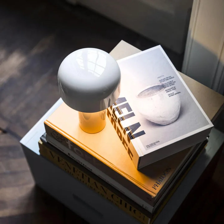 White glossy mushroom lamp glowing warmly on a stack of large coffee table books 21