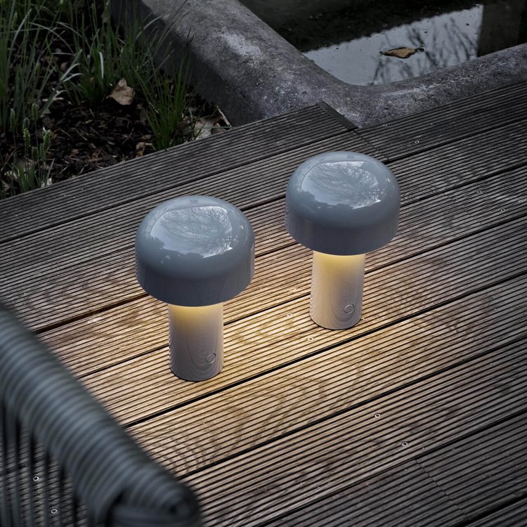 Two gray mushroom-shaped lamps glowing softly on an outdoor wooden deck at dusk 22