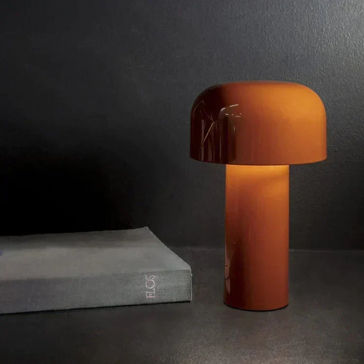 Glowing burnt-orange lamp on a dark surface next to a gray hardcover book 8