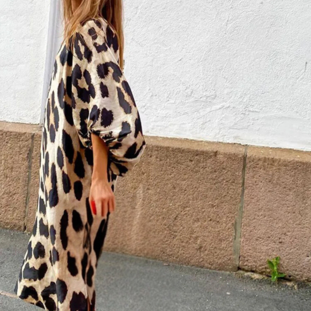 Frau im langen, beige-schwarzen Leopardenmuster-Kleid auf der Straße.