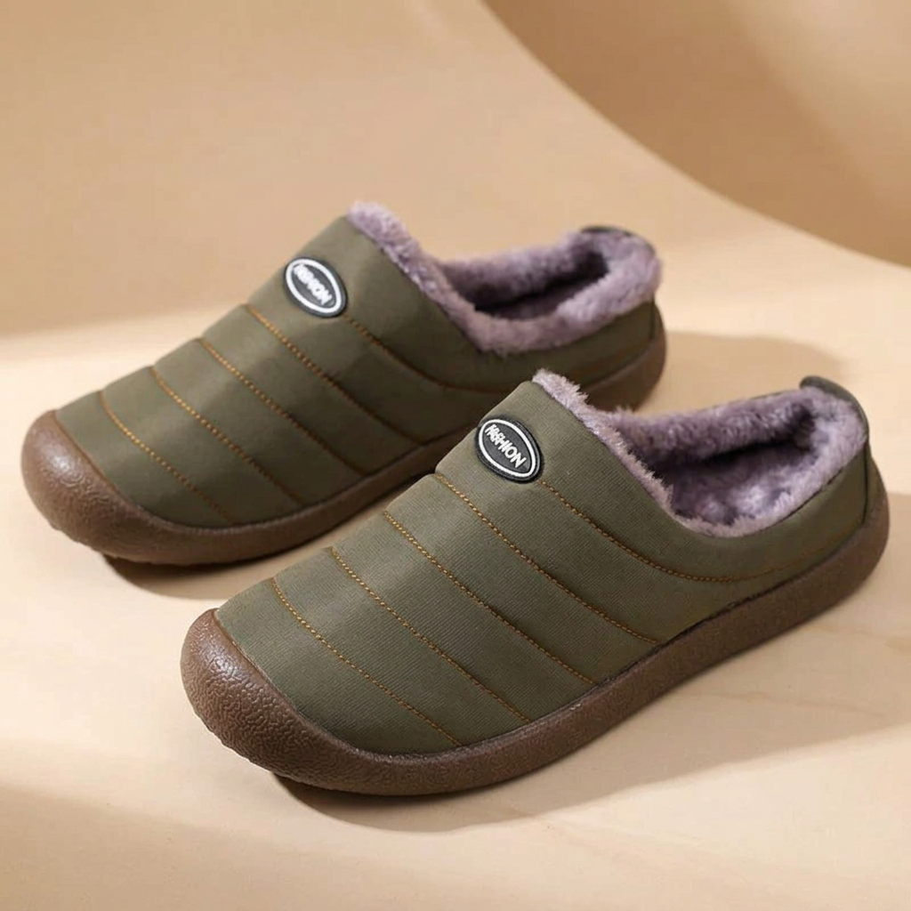 Pair of olive green quilted slippers with lavender-gray fleece on a beige curved backdrop 17