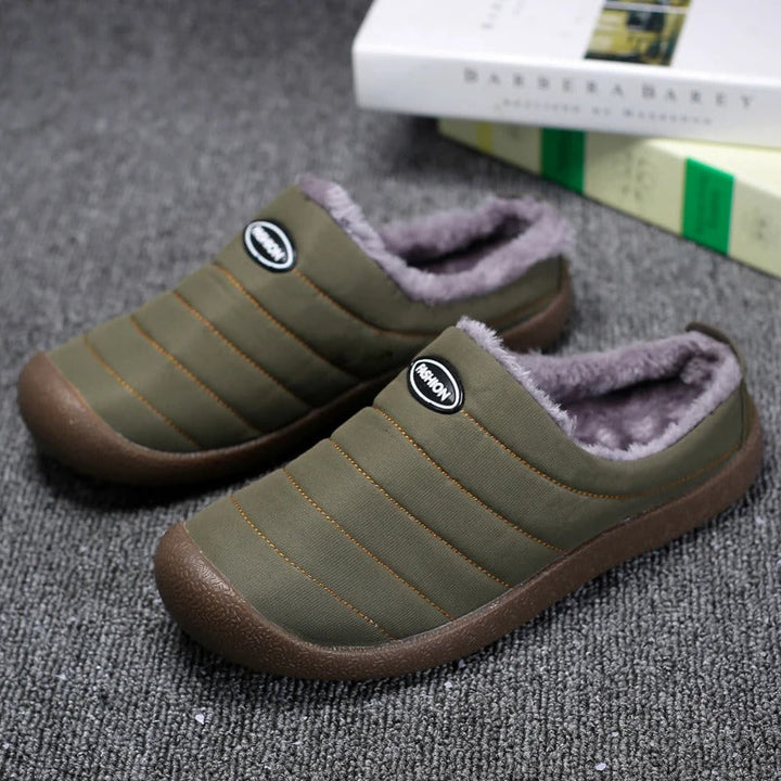 Pair of olive green quilted fleece-lined slippers on gray carpet, with books behind 2