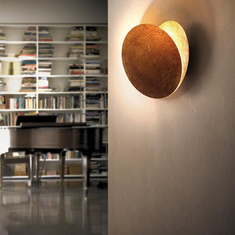 Side view of the lamp on a plain wall, glowing behind a bookshelf and piano 4